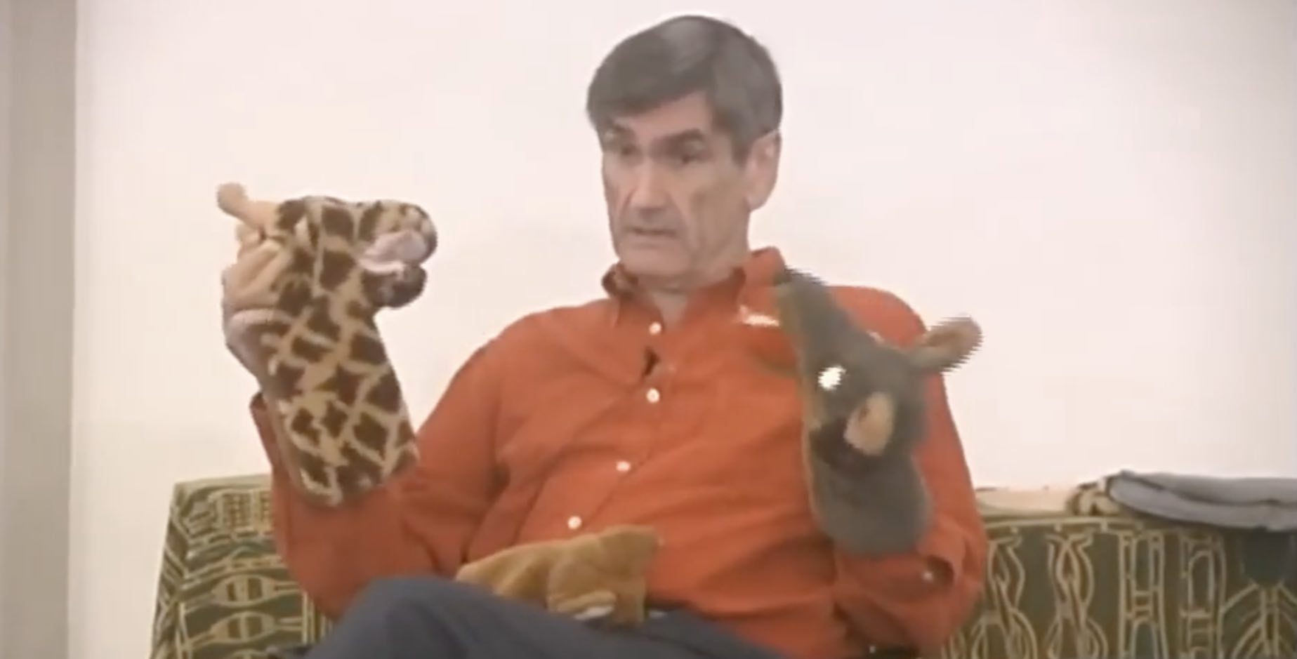 Marshall Rosenberg holding a puppet giraffe and a puppet jackal while teaching NVC